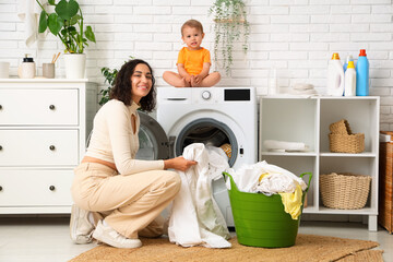 Wall Mural - Mother with her cute little baby doing laundry in bathroom