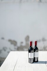 Wall Mural - Photograph of a white table with 2 bottles of red wine, with a grey wall degraded to white in the background