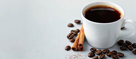 Fototapete - Close up of a white coffee cup filled with black coffee garnished with cinnamon and whole beans against a plain background with copy space image