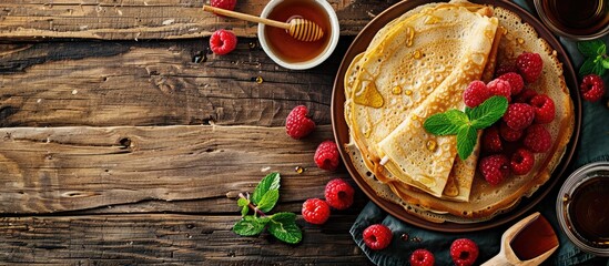 Fototapete - Rural breakfast spread viewed from the top Thin crepes or pancakes with raspberries honey and mint on rustic wood backdrop with room for text ideal for a copy space image