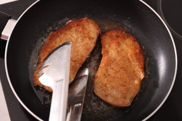 Wall Mural - Schnitzels cooking in frying pan on stove, top view