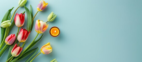 Poster - A serene setting with vibrant tulips a candle and a pale blue backdrop allows room for text in this flat lay copy space image