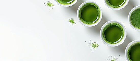 Poster - Top view of small cups of matcha tea ready to drink on a white background with copy space image