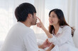 ©  NCST Studio - Asian woman is touching the nose of her husband while they are both smiling and relaxing in bed