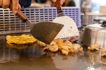 The chef is stirring the delicious Teppanyaki chicken and the aroma is overwhelming