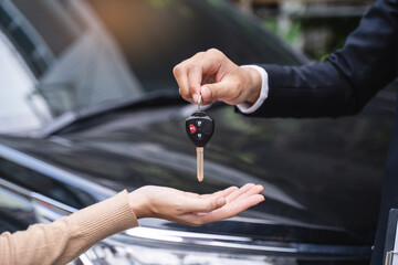 Wall Mural - transportation rental automotive business concept. Close up hands of rental auto agent giving car remote key to client to travel sightseeing.