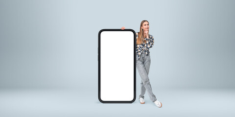 Poster - Woman leaning on a giant phone with a blank screen on a gray bac