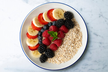 Canvas Print - Delicious and healthy bowl of oatmeal with red fruits, raspberries, blueberries, strawberries and banana.