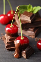 Wall Mural - Fresh cherries with chocolate on grey wooden table, closeup