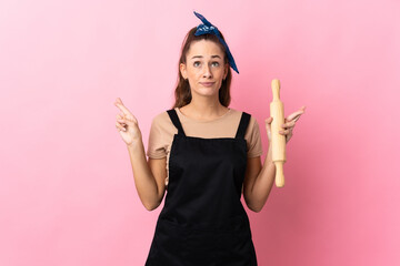 Wall Mural - Young woman holding a rolling pin with fingers crossing and wishing the best