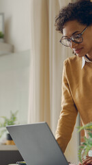 Wall Mural - Female freelancer working laptop remotely while standing at home. Distance work concept