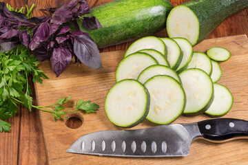 Wall Mural - Sliced green zucchini on cutting board among the greens