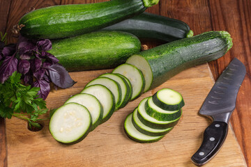 Wall Mural - Sliced green zucchini on cutting board among the greens