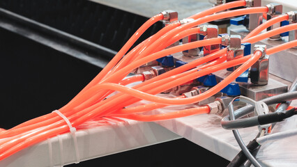 Poster - Close-up of precise industrial equipment with pneumatic components: orange plastic tubes with connectors. Industrial concept background.