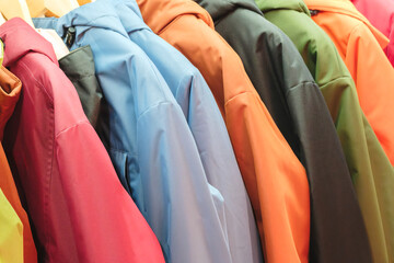 Poster - A row of colorful jackets hanging on a rack. The jackets are of different colors and styles, and they are all hanging next to each other. Concept of variety and diversity