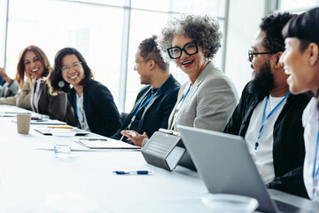 Wall Mural - diverse colleagues laughing and engaging in a corporate meeting in a bright office environment
