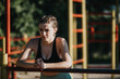 © qunica.com - Young woman resting after exercise at outdoor fitness park. She looks determined and focused while taking a break from her workout routine.