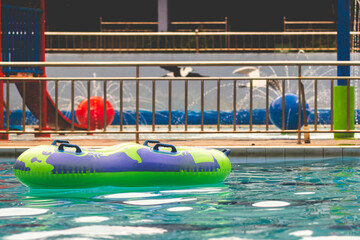 Inflatable green ring in swimming pool. Green ring swimming pool with handle float in blue clear water at sunny day