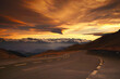 © Nataliia - Mountain road winding through a dramatic sunset landscape with snow-capped peaks in the background