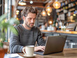 © Kowit - A man is sitting at a table with a laptop and a cup of coffee