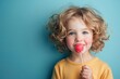 © Michael - little girl enjoying eating lollipop candy on a blue background