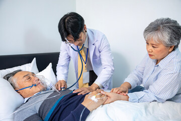 Senior male patient with nasal cannula oxygen is getting diagnosis from hospice doctor for his lung cancer at home with his supporting wife together for palliative medical treatment in his final hour