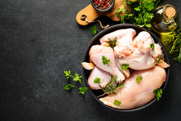 Wall Mural - Chicken wings, drumsticks and breast with herbs and spices on black background. Top view with copy space.