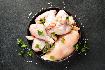 Sticker - Raw Chicken meat with herbs and spices on black. Different part of chicken - fillet, wings, drumsticks. Top view with copy space.