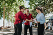 © qunica.com - Group of three businesspeople talking and collaborating on documents in a park setting. Professional teamwork and outdoor meeting.