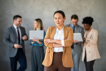 Wall Mural - Portrait of successful business woman, entrepreneur while multiethnic colleagues working background.