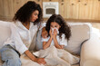 © Home-stock - Sad caring mother worries about her sick little daughter, sitting near girl on couch, child has a cold, flu, holding napkin, sneezes, coughs, runny nose