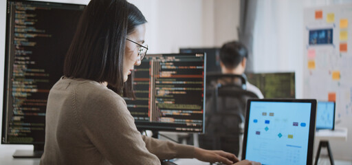 young adult asian male, female software developer coding program on desktop computer. man, woman wor