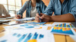 © Infinite Art Labs - Young Couple Consults Financial Advisor: Navigating Financial Planning with Charts, Graphs, and Documents