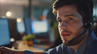 © Sadia - Young Man Wearing Headset Working at Desk in Modern Office During Evening Hours