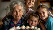 © ChaoticMind - A joyful elderly woman celebrates her birthday in the warm company of her grandchildren, creating precious memories around a cake, with heartfelt smiles and love.