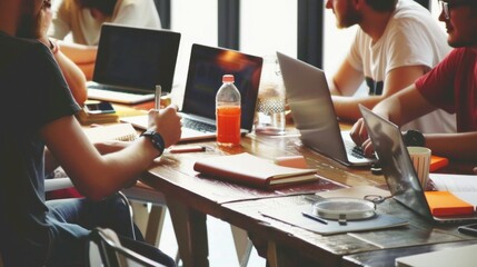Poster - A group of people are sitting around a table with laptops