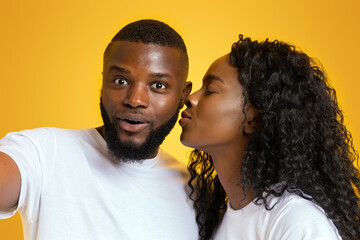 Wall Mural - First kiss. African american couple in love taking selfie on yellow studio background