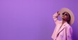 © Olga - Woman wearing pink clothes and hat in dark sunglasses looking up on pastel purple background, fashion photography. Wide banner with copy space for web design or beauty magazine article.