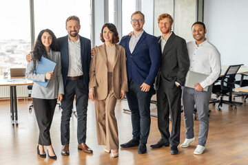 Aufkleber - A group of six colleagues stand in a modern office, smiling, looking at the camera. They are a diverse group of professionals in business attire, demonstrating a company culture that values inclusion.
