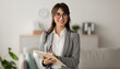 © Prostock-studio - Happy professional middle eastern female psychologist writing in clipboard, looking and smiling at camera, working in modern office. Psychotherapy services, mental health professional concept