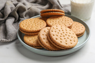 Wall Mural - Tasty sandwich cookies and glass of milk on white table, closeup