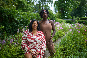 Portrait of two women in a lush green park on a summer day.