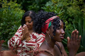 Portrait of two women meditating in a park surrounded by lush greenery.