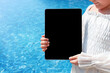 © Vasleriia Kuznetsova - Tablet with copy space in the hands of a child near the pool