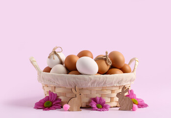 Wall Mural - Wicker basket with Easter eggs, chrysanthemum flowers and bunnies on lilac background