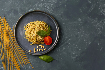 Wall Mural - Plate with tasty pesto pasta and tomatoes on dark grunge background