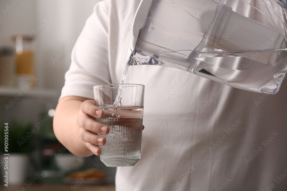 Woman pouring pure water from filter jug into glass