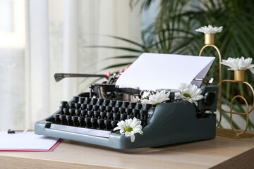 Wall Mural - Vintage typewriter with paper sheet and flowers on wooden table in room