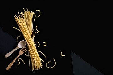 Wall Mural - Flat lay of spaghetti for cooking italian pasta over black background