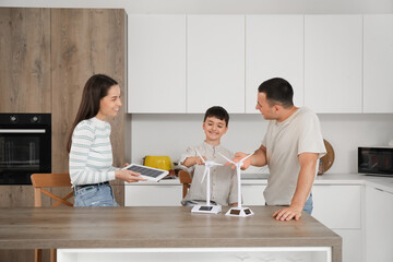 Canvas Print - Happy family with wind turbine models and portable solar panel in kitchen